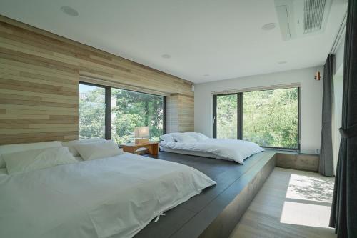 2 camas en un dormitorio con ventanas grandes en Scenery after Rain en Yangyang