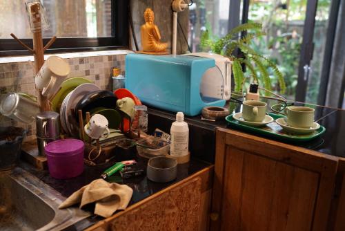 a kitchen counter with a sink with dishes and a microwave at Happy House BnB Bromo backpacker in Probolinggo