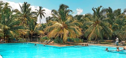 a large swimming pool with palm trees in the background at Lagoon Paradise Beach Resort in Tangalle