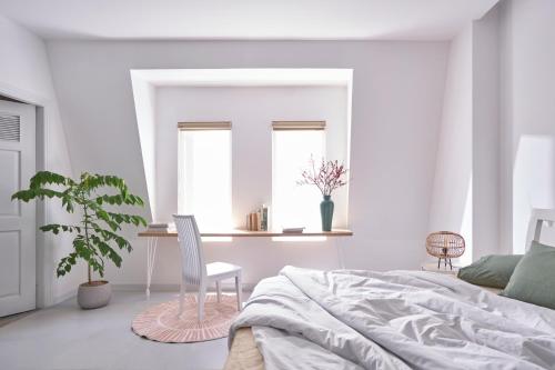 a bedroom with a bed and a chair and a plant at M Village Living Nguyễn Văn Hưởng in Ho Chi Minh City