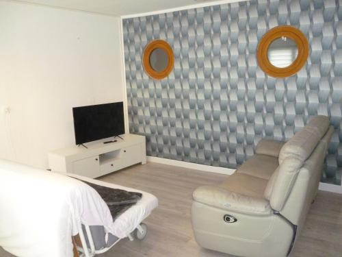 a bedroom with a couch and a chair and a television at Flobart grand appartement à Sangatte au rdc et à 30 metres de la plage in Sangatte