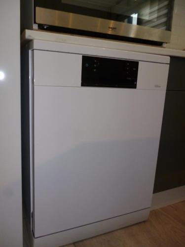 a white dishwasher with a microwave on top of it at Flobart grand appartement à Sangatte au rdc et à 30 metres de la plage in Sangatte