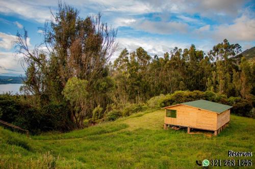 a small wooden house on a hill with a field at Villa Maria in Guatavita