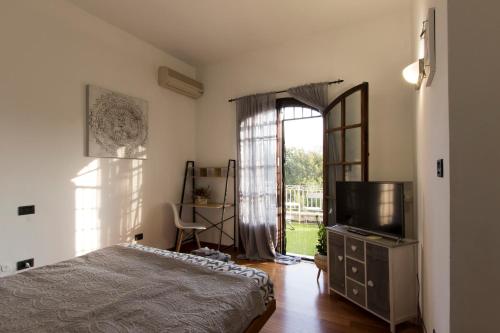 um quarto com uma cama, uma televisão e uma janela em Ca'stello23 em Sala Bolognese