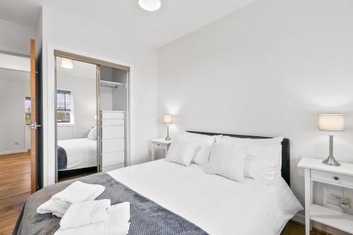 a white bedroom with a large bed with white pillows at Aspen Apartment in Helensburgh