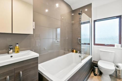uma casa de banho com uma banheira, um WC e um lavatório. em Aspen Apartment em Helensburgh