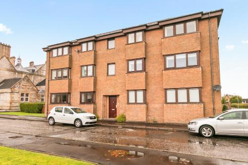 two cars parked in front of a brick building at Aspen Apartment in Helensburgh