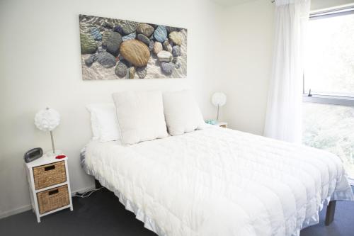 a bedroom with a white bed and a window at Oceans Resort Whitianga in Whitianga