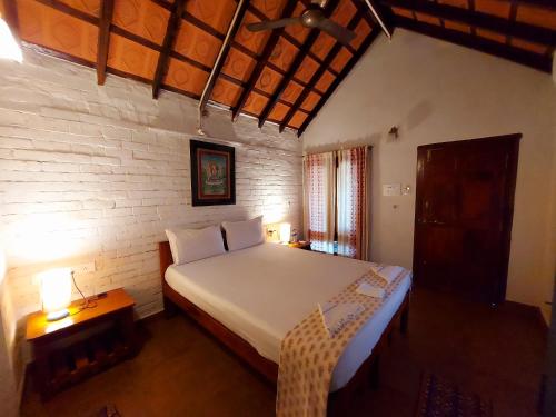 - une chambre avec un grand lit blanc et une table dans l'établissement OmBodhi Retreat, à Kumta