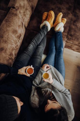 two people laying on the floor holding cups of coffee at Almdorf Omlach, Fanningberg in Weisspriach