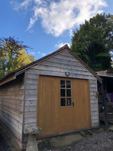 a large wooden garage with a door on it at Cosy 1 bedroom country lodge with free parking in Watlington