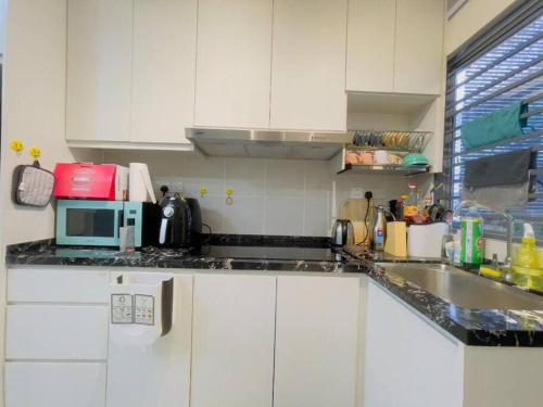 a white kitchen with a sink and a microwave at Double Storey Sweet Home 12pax @ Puncak Alam in Kuala Selangor