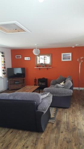 2 Sofas im Wohnzimmer mit orangefarbenen Wänden in der Unterkunft Torgoyle Cottage in Inverness