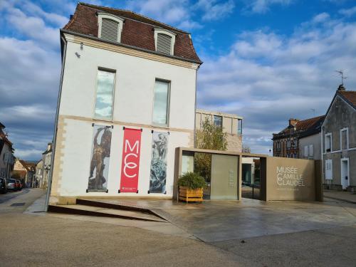 a white building with windows on a street at Le Relais de l'endormie in Nogent-sur-Seine