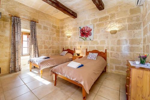 a bedroom with two beds in a stone room at Ponderosa Holiday Home in Birbuba