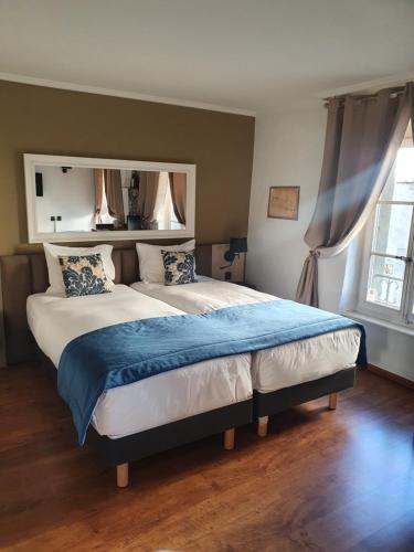 a bedroom with a large bed with a blue blanket at L'Hôtel by Hostellerie du Château in Rolle