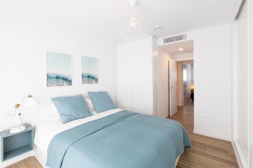 a bedroom with a bed with a blue blanket at Fabuloso Apartamento nuevo con Parking y Piscina in Málaga