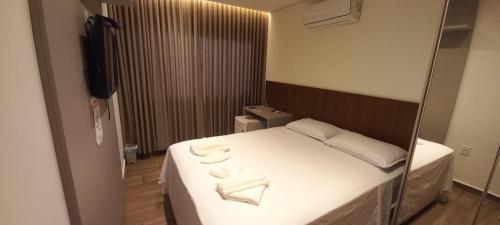 a bedroom with a large white bed with a mirror at Pousada Flor de Alter in Alter do Chao