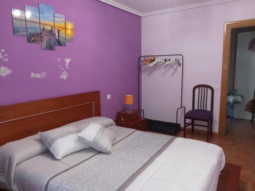 a bedroom with a bed with purple walls and a chair at San Martín in Sotés