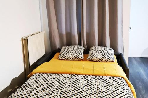 uma cama com duas almofadas num quarto em Le Jules Val - Studio cosy en résidence + Parking + Wi-fi em Évry-les-Châteaux
