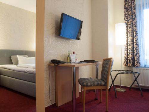 a room with a desk with a tv on the wall at Hotel & Restaurant Waldschlösschen in Kyritz