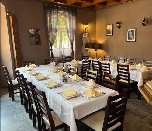 een eetkamer met een lange tafel met witte tafelkleden bij Zur Eldenburg in Lübz