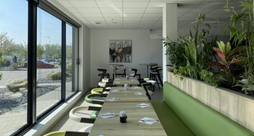 a conference room with a long table with chairs and plants at ATOLON PARK HOTEL in Brumath
