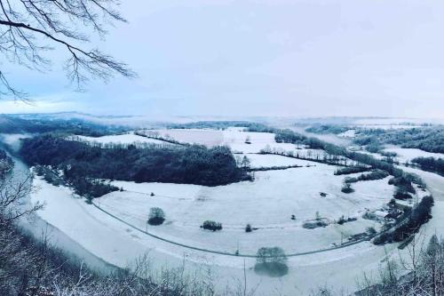 a snow covered field with trees and a river at Au Numéro 5 in Tilff
