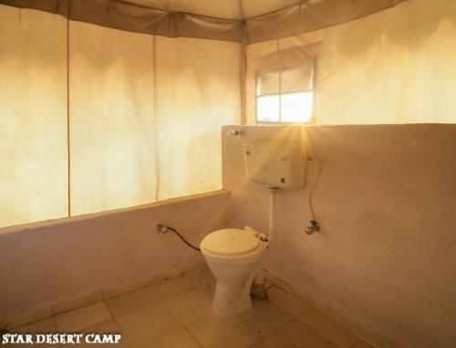 a bathroom with a toilet and a window at Star Desert Camp Jaisalmer in Jaisalmer
