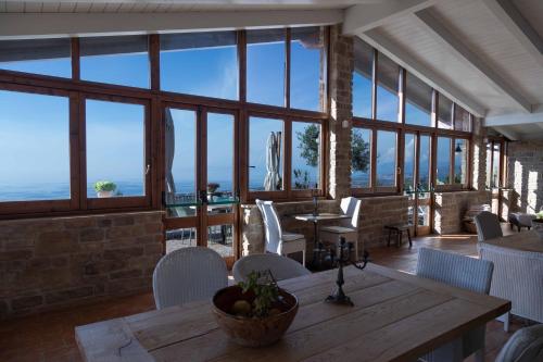- une salle à manger avec une table, des chaises et des fenêtres dans l'établissement La Pastorella, à Maierà