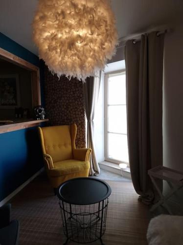 a living room with a chair and a large light fixture at Petit cocon quartier historique Chaumont in Chaumont