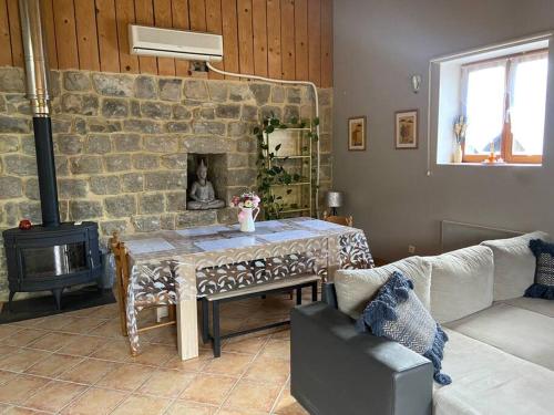 sala de estar con mesa y chimenea de piedra en Gite a la ferme avec jacuzzi et sauna en Villefloure