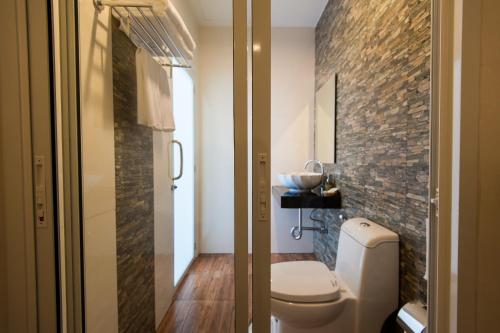 a bathroom with a toilet and a brick wall at Jinda Resort in Nai Yang Beach