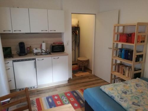 a kitchen with white cabinets and a room with a bed at Steirerhof in Bad Aussee