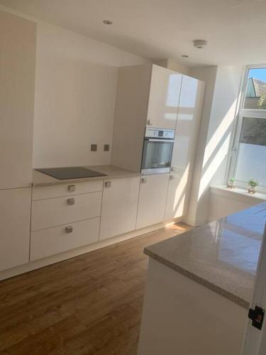 a kitchen with white cabinets and a counter top at The Victorian Apartment in Dundee