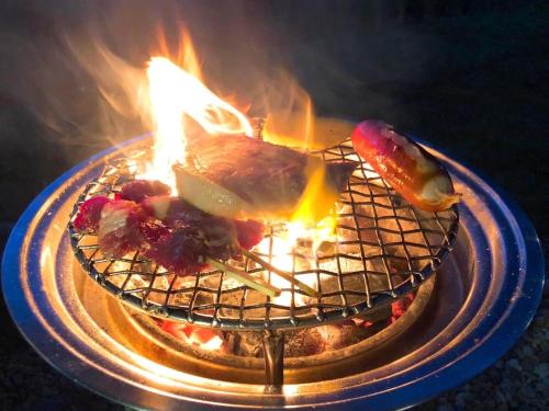 a plate of food on a grill with fire at The Villa Sai yok noi in Khlong Luang