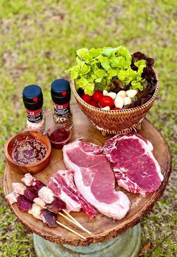 a plate with meat and vegetables and a basket of salad at The Villa Sai yok noi in Khlong Luang
