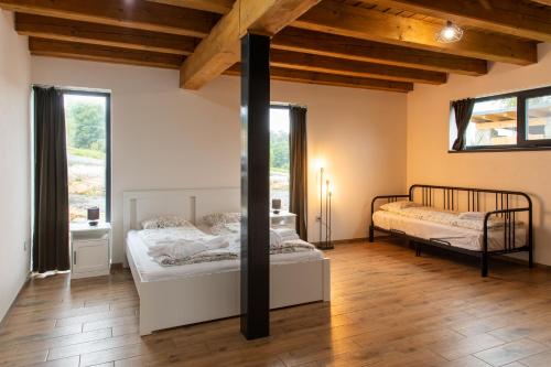 two beds in a room with wooden ceilings and windows at Chata Viola in Dolní Morava