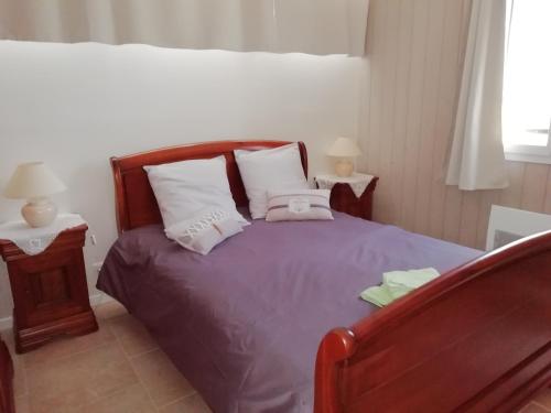 ein Schlafzimmer mit einem Bett mit lila Bettwäsche und weißen Kissen in der Unterkunft La Maison de Joindy in Saint-Cyprien