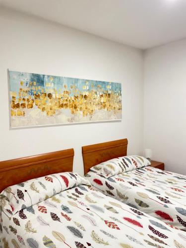 a bedroom with two beds and a painting on the wall at Apartamento a pie de playa en Mogro in Mogro