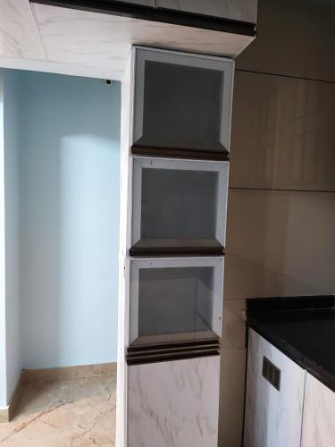 a refrigerator with three empty shelves in a kitchen at Kamadhenu Residency Homestay & Service Apartment Coorg Madikeri in Madikeri
