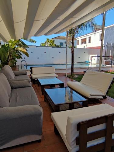a patio with couches and tables on a patio at Apartamento privado con piscina y jardin compartidos. in Valencina de la Concepción