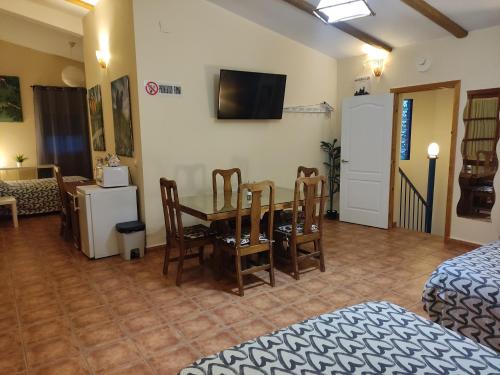 a room with a table and chairs and a tv at Apartamento privado con piscina y jardin compartidos. in Valencina de la Concepción