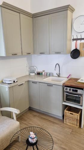 a small kitchen with white cabinets and a table at Lovely studio with balcony in Rechovot