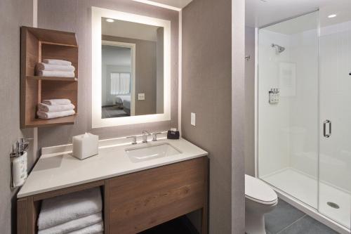 a bathroom with a sink and a toilet and a mirror at Staybridge Suites Wilmington Downtown by IHG in Wilmington