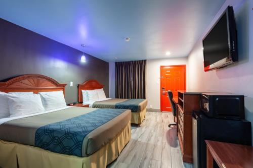 a hotel room with two beds and a flat screen tv at Summit Inn - Houston Medical Center - NRG Park in Houston