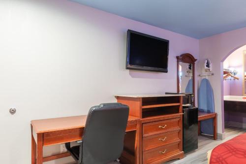 a bedroom with a desk with a computer and a television at Summit Inn - Houston Medical Center - NRG Park in Houston