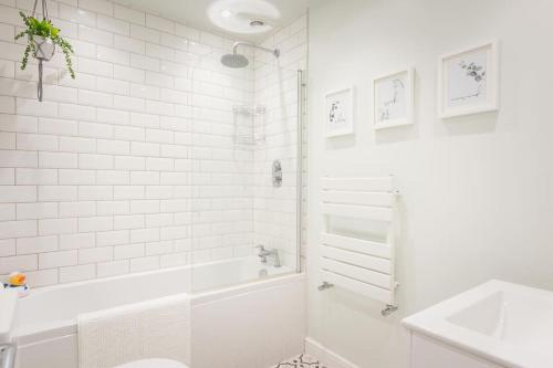 Baño blanco con bañera y lavamanos en *Brand New* Lemon Tree Cottage en Torquay