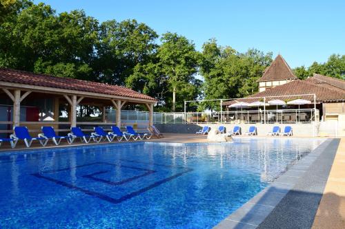 une piscine avec des chaises bleues et un bâtiment dans l'établissement Résidence Les Hauts de Marquay, à Marquay