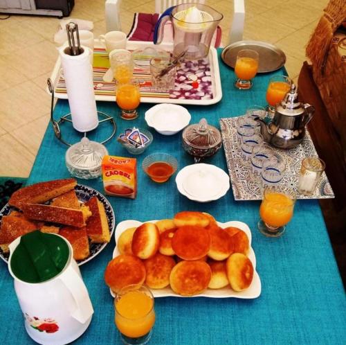 einen blauen Tisch mit Platten aus Gebäck und Orangensaft in der Unterkunft Azur Tafraout in Tafraout